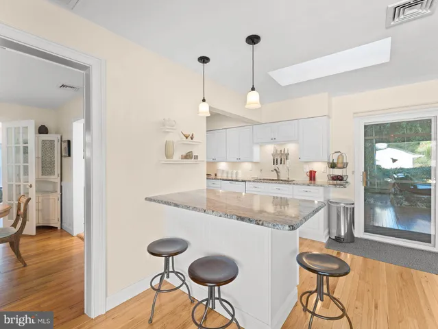 a kitchen with stainless steel appliances granite countertop a sink a refrigerator and a wooden floor