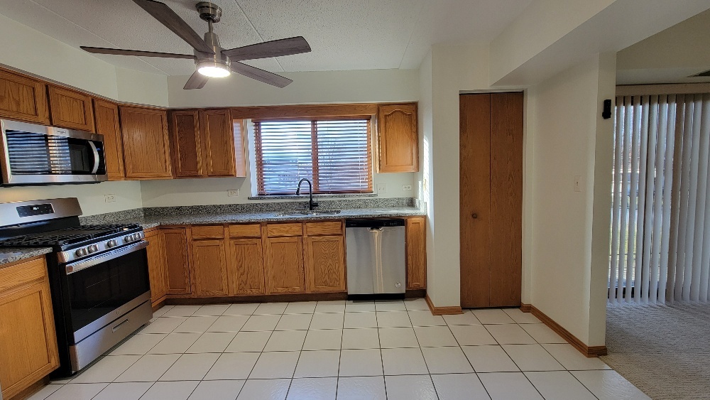 18100 Rita Road, Unit 2D Tinley Park, IL 60477 - Photo 6 of 28 a kitchen with granite countertop a stove a sink and a microwave