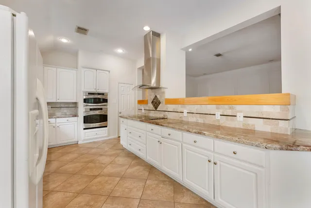 a large kitchen with granite countertop a sink and white cabinets