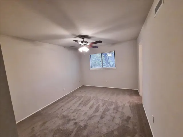 an empty room with a chandelier fan and windows