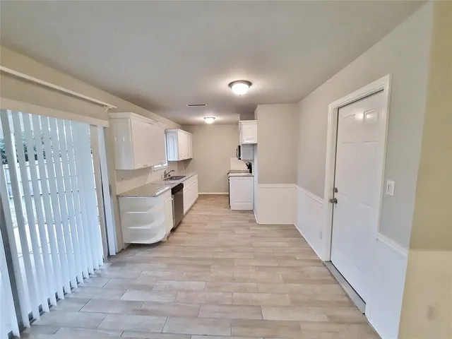 a view of a kitchen with white cabinets and wooden floor