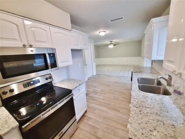 a kitchen with stainless steel appliances kitchen island granite countertop a stove a microwave and a sink