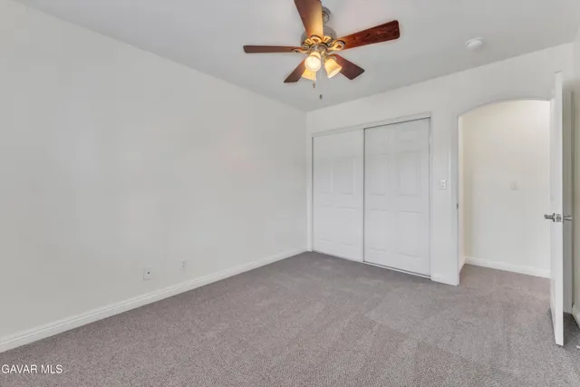 an empty room with chandelier fan and windows