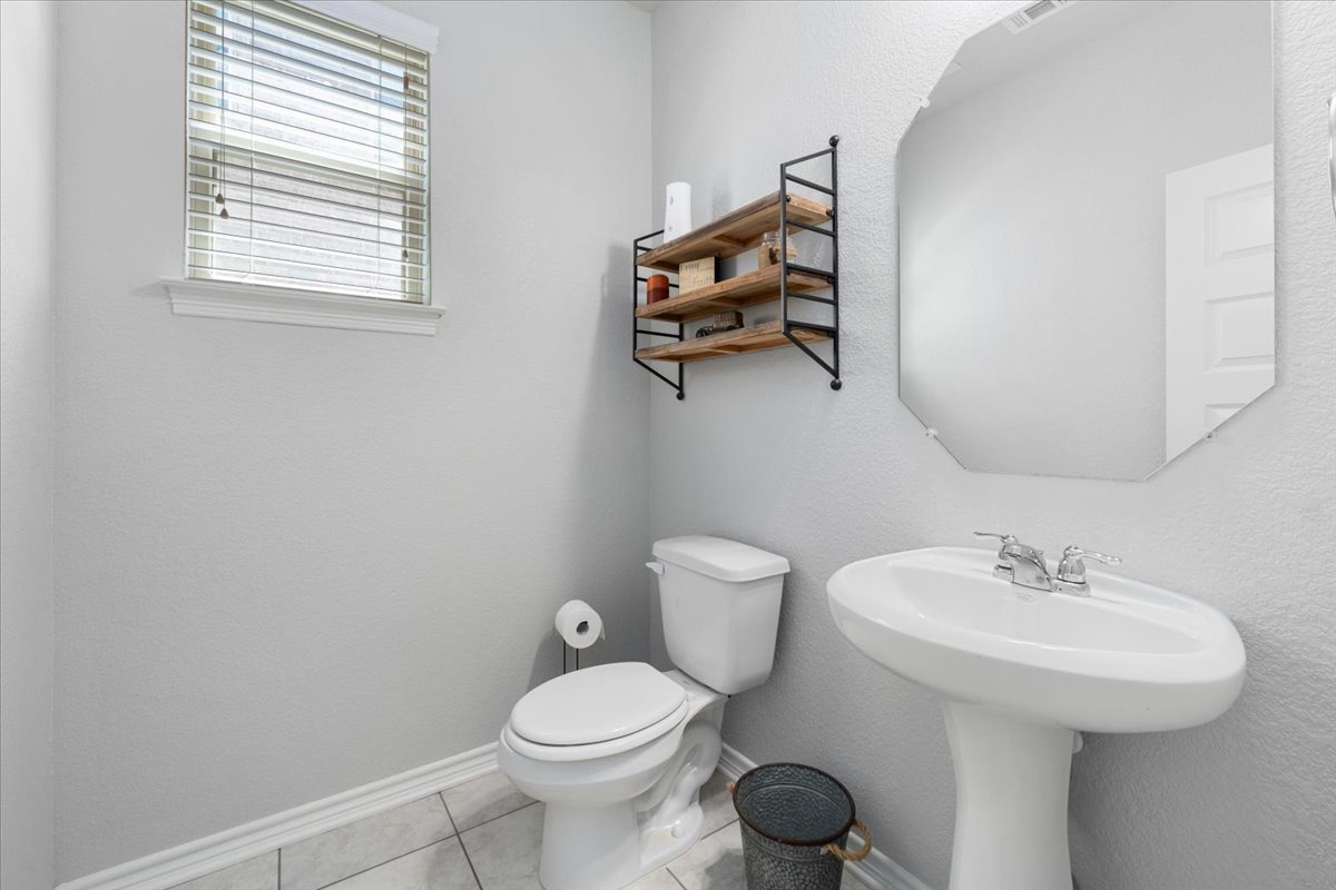 5408 Vanner Path Georgetown, TX 78626 - Photo 28 of 34 Pedestal sink with chrome faucet, octagonal wall mirror, and a wall-mounted shelving unit featuring wood-finish shelves and a black metal frame