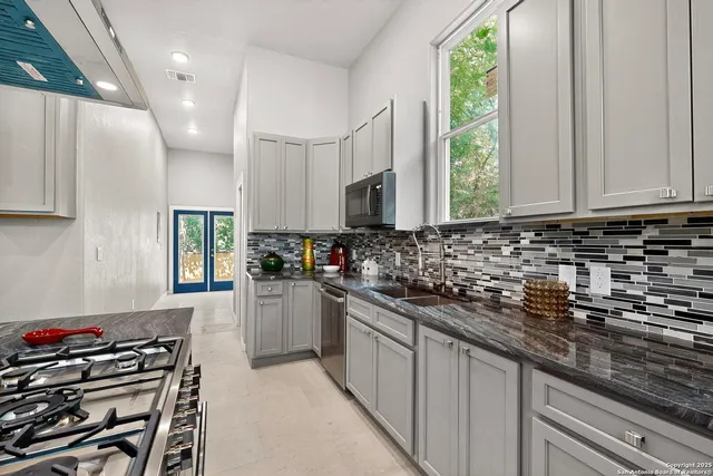 a kitchen with granite countertop a stove a sink dishwasher and a microwave oven with white cabinets