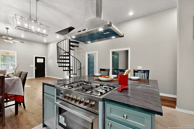 a room with stainless steel appliances kitchen island granite countertop a sink a stove a dining table and chairs