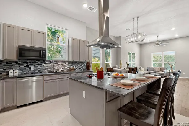 a kitchen with stainless steel appliances a dining table chairs and a refrigerator