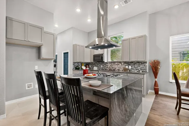 a kitchen with stainless steel appliances granite countertop a stove a sink island a dining table and chairs