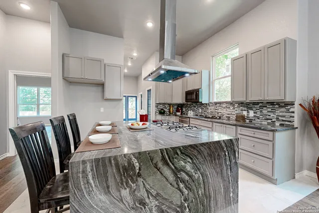 a kitchen with stainless steel appliances kitchen island granite countertop a stove a sink and a refrigerator