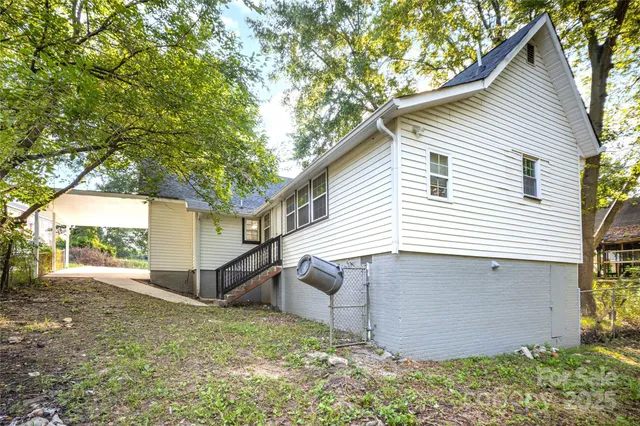 a view of a white house next to a yard and a large tree
