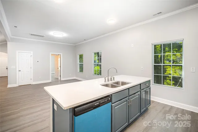 a kitchen with a sink window and wooden floor