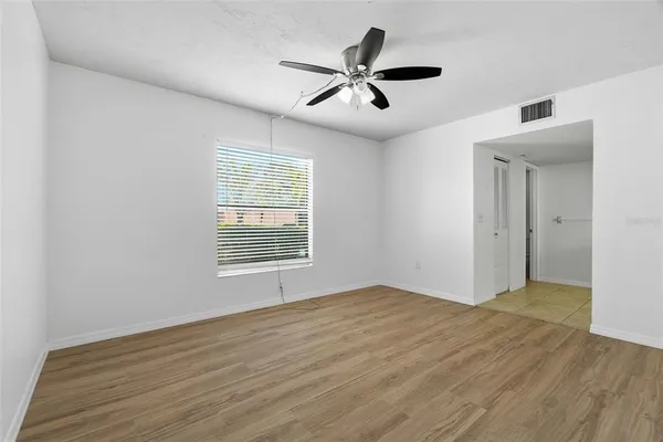 a view of empty room with wooden floor and ceiling fan