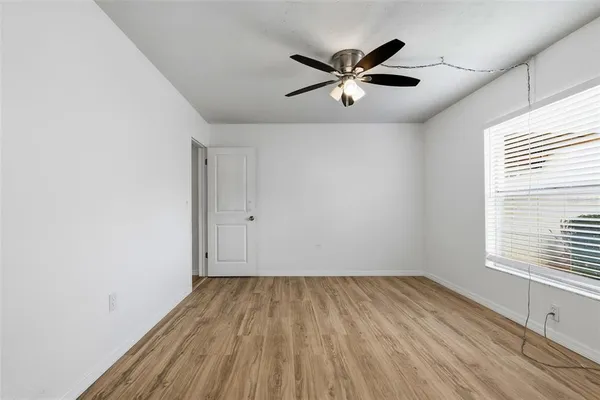 a view of empty room with wooden floor and window