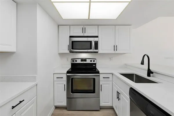a kitchen with cabinets stainless steel appliances and sink