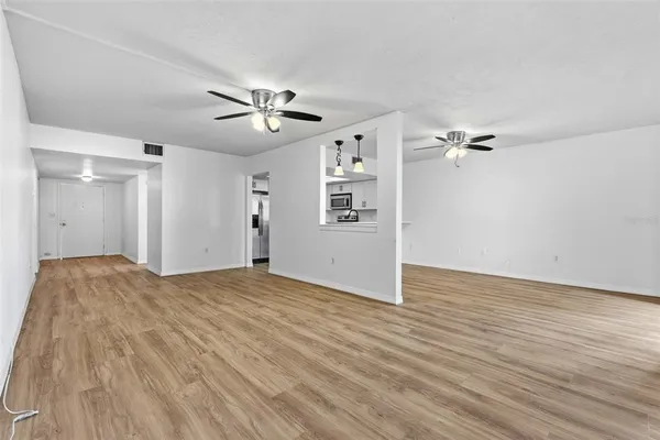 a view of empty room with wooden floor and ceiling fan