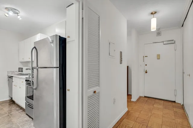 a view of a refrigerator in kitchen and an empty room