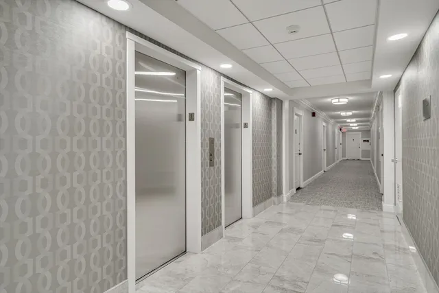 a large white kitchen with stainless steel appliances kitchen island a white counter space and a fireplace
