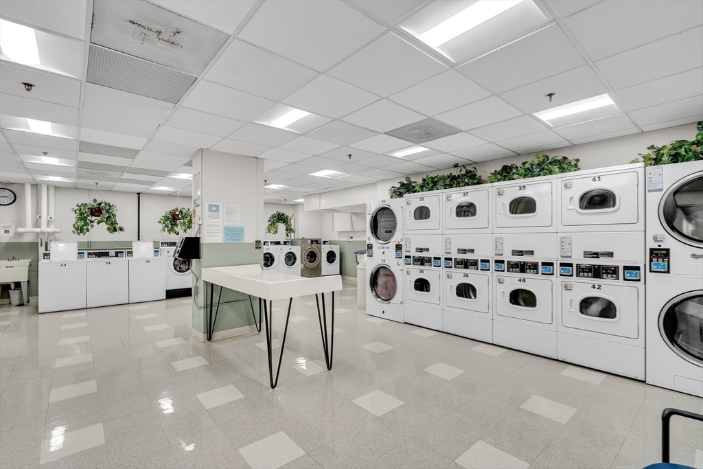 9 Hawthorne Place, Unit 5K Boston, MA 02114 - Photo 26 of 37 a large white kitchen with stainless steel appliances kitchen island a white counter space and a fireplace