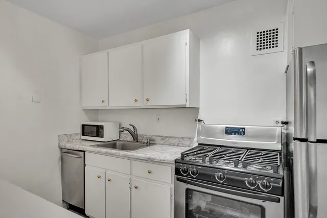 a kitchen with granite countertop white cabinets and stainless steel appliances