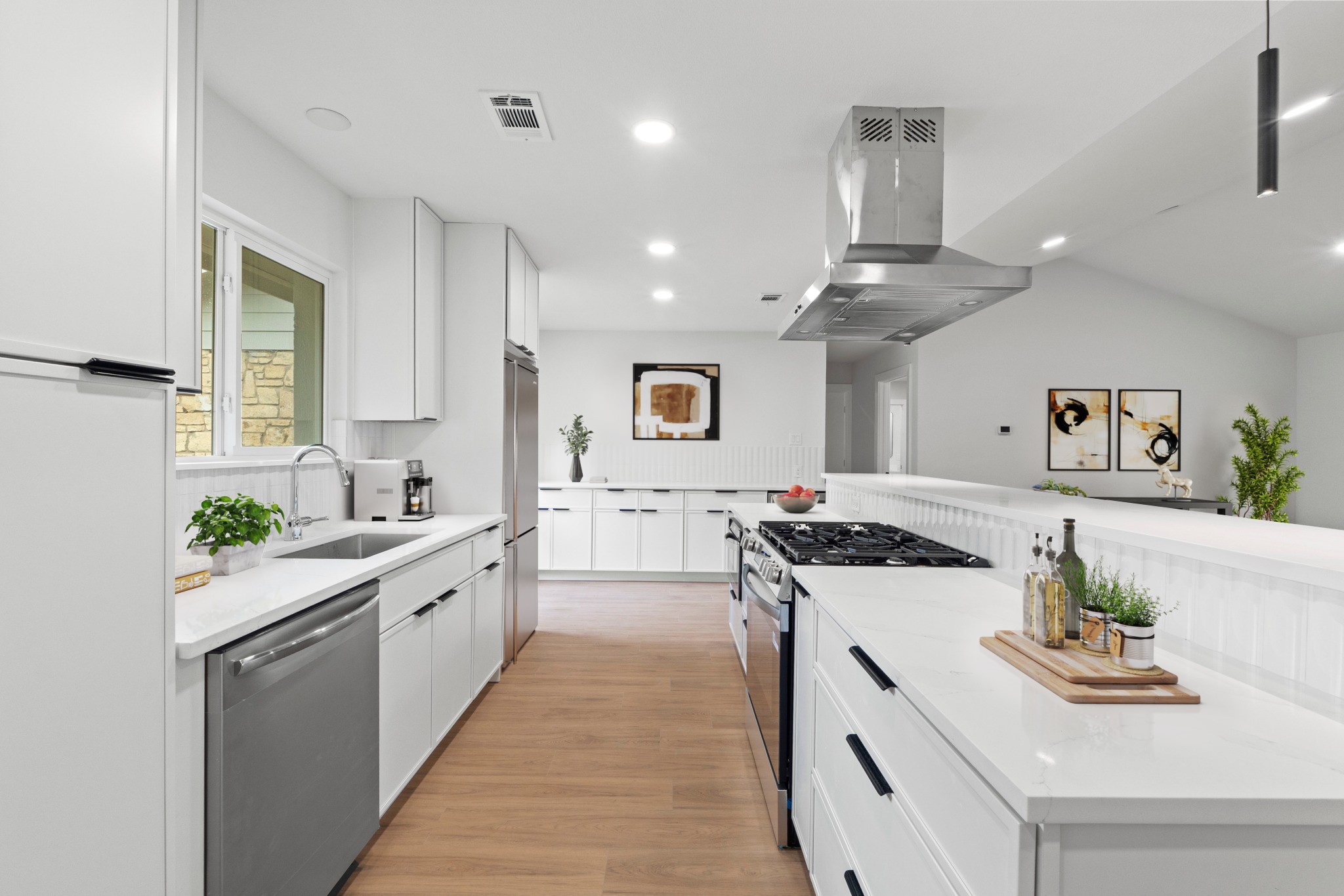 1608 Springer Lane Austin, TX 78758 - Photo 9 of 35 Modern kitchen featuring white cabinetry, stainless steel appliances, light-toned wood-finish flooring, recessed lighting, and a window with exterior stone visible