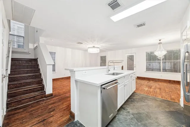 a large white kitchen with wooden floor and white appliances