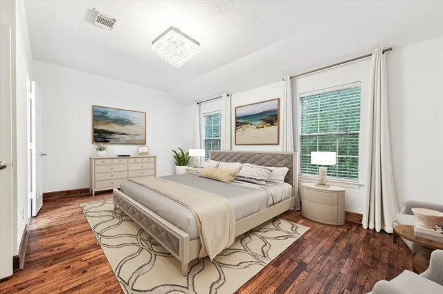 a bedroom with a large bed a chandelier and windows