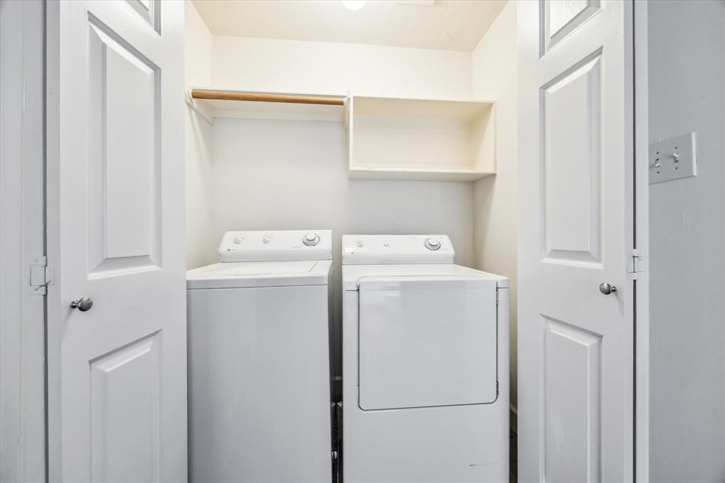 227 Blushwood Place Spring, TX 77382 - Photo 27 of 30 Utility (2nd Floor). Convenient in-home laundry nook with full-size washer and dryer, upper shelving, and hanging space—neatly tucked behind double doors.