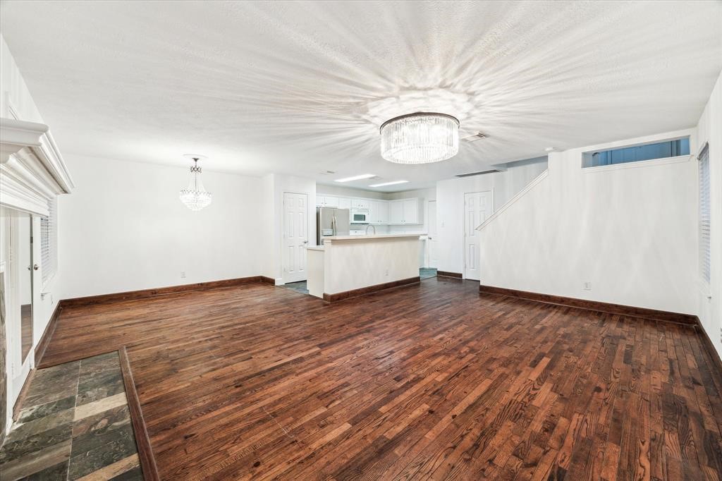 227 Blushwood Place Spring, TX 77382 - Photo 10 of 30 Beautifully unified living, dining, and kitchen areas with warm hardwoods, sleek white cabinetry, and designer lighting—offering style and flow in one open space.