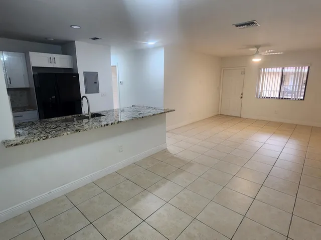 an empty room with kitchen and chandelier