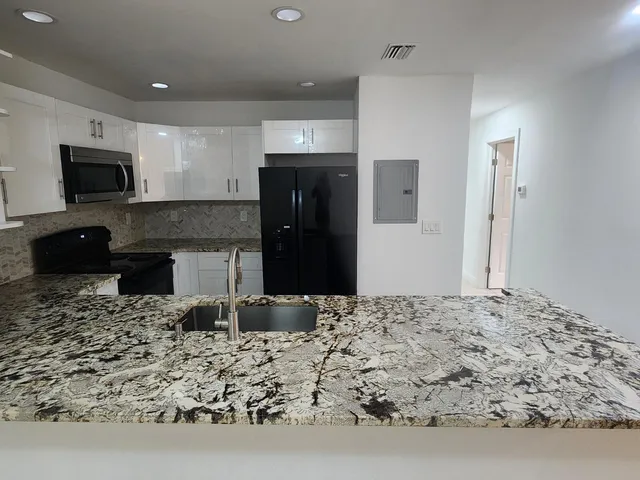 a kitchen with kitchen island sink and refrigerator