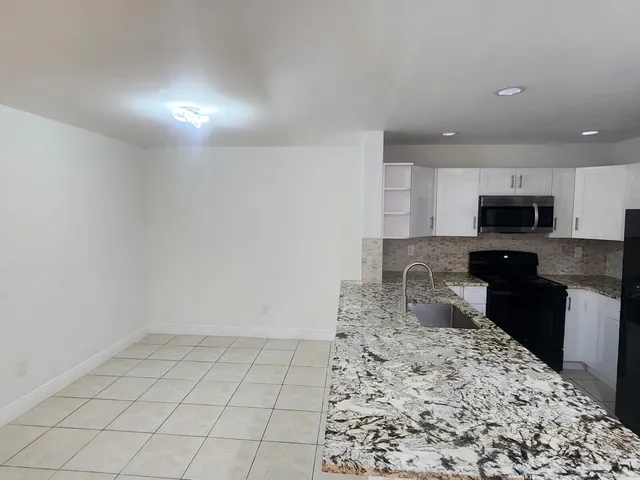 a kitchen with a sink a stove top oven and cabinets