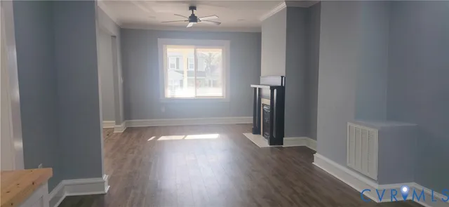 an empty room with wooden floor entryway and kitchen view