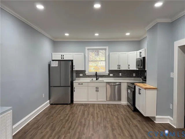 a kitchen with stainless steel appliances granite countertop a sink and a granite counter tops with wooden floors