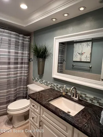 a bathroom with a granite countertop sink mirror vanity and toilet