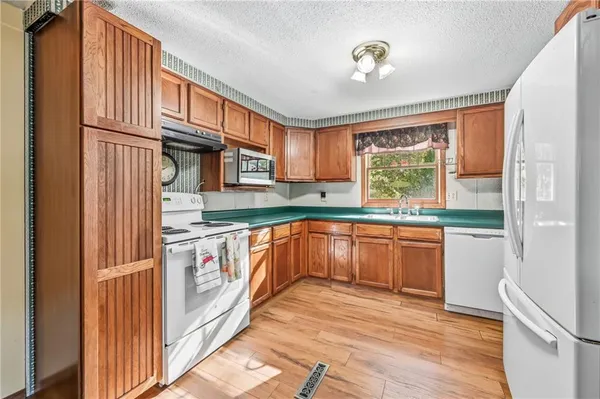 a kitchen with granite countertop stainless steel appliances a refrigerator cabinets and a window