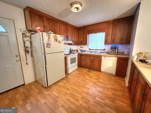 a kitchen with stainless steel appliances granite countertop a refrigerator sink and wooden cabinets