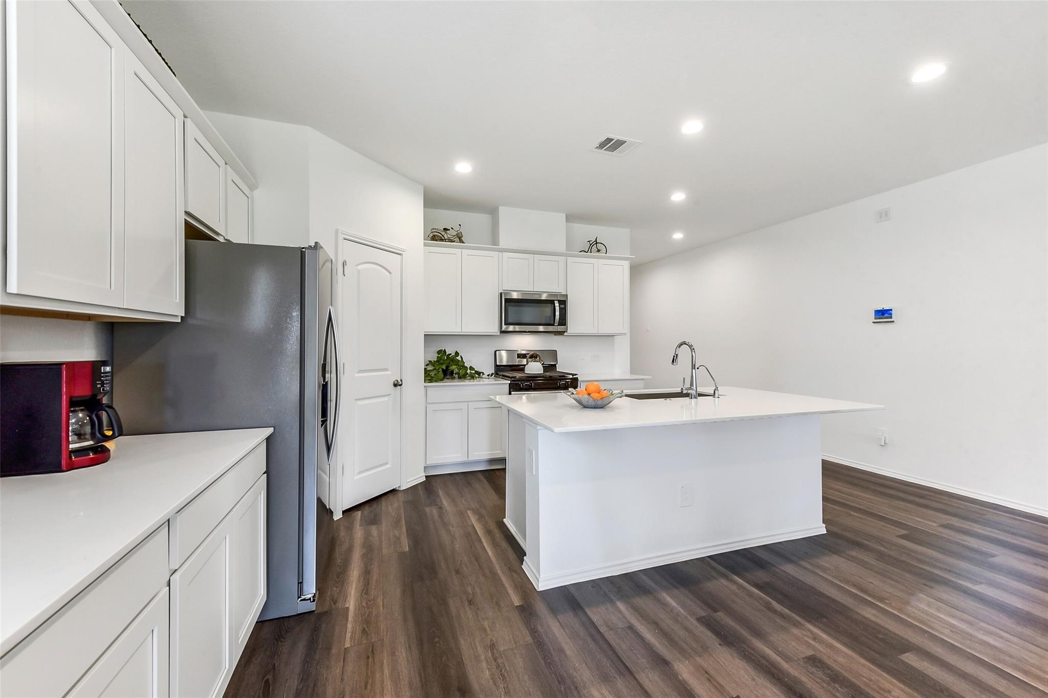 4985 Blue Beetle Rdg Drive Katy, TX 77493 - Photo 6 of 40 a kitchen with stainless steel appliances a refrigerator a sink dishwasher a stove and white cabinets with wooden floor