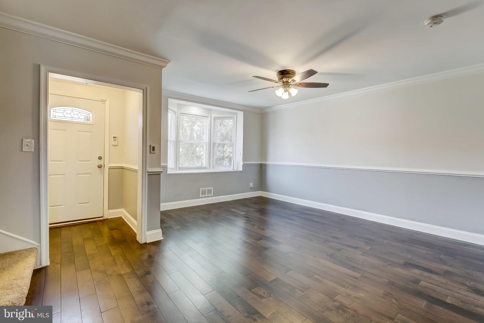 1419 Kingsway Road Baltimore, MD 21218 - Photo 6 of 38 an empty room with wooden floor chandelier fan and windows