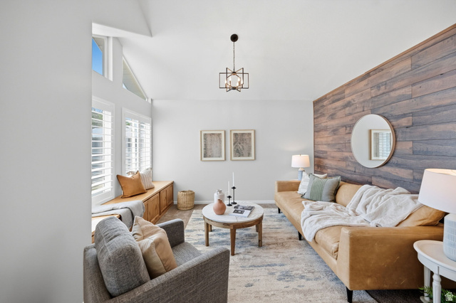 3732 Campbell Road Tooele, UT 84074 - Photo 12 of 69 Vaulted ceiling featuring a contemporary chandelier, a built-in window seat with storage, white plantation shutters, a wood-paneled accent wall, and wood-finish flooring