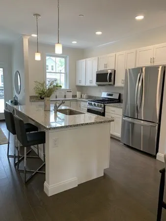 a kitchen with stainless steel appliances granite countertop a refrigerator a stove a sink a dining table and chairs