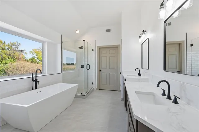 a bathroom with a tub a sink a window and a shower