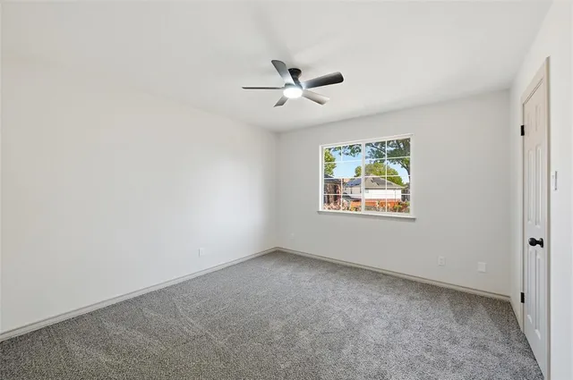 an empty room with window and ceiling fan