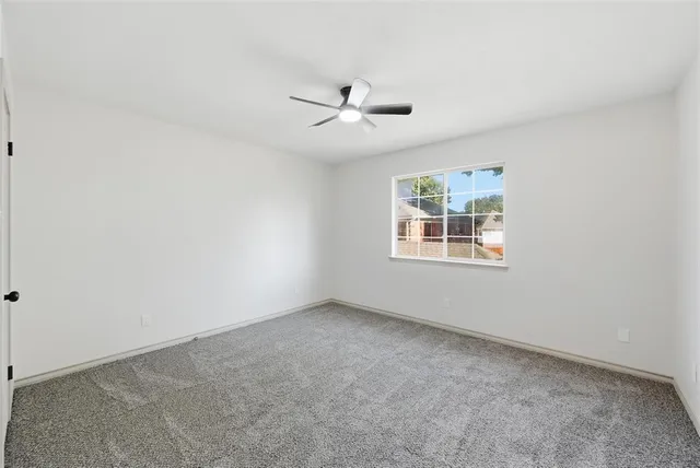 an empty room with a window and ceiling fan