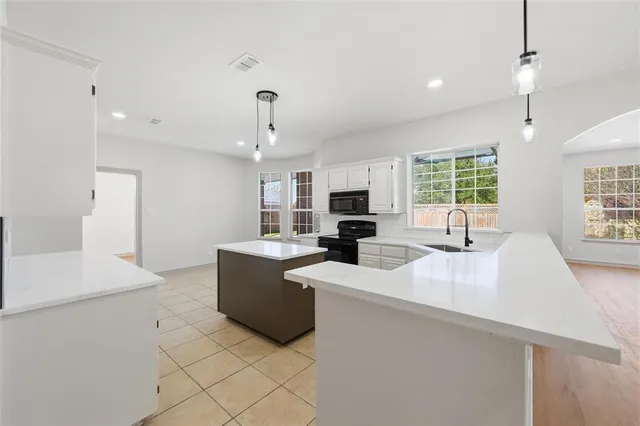 a large white kitchen with a large window a sink and stainless steel appliances