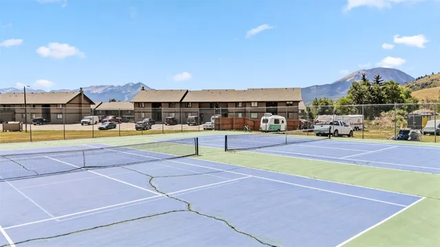 a view of swimming pool with lawn chairs and large trees