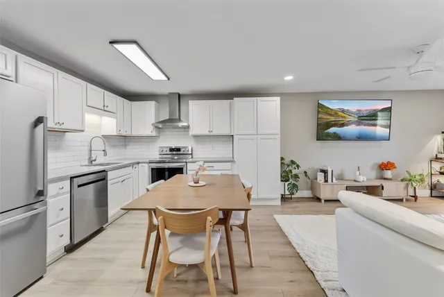 a kitchen with stainless steel appliances granite countertop a stove a sink a refrigerator a microwave oven with a dining table and chairs