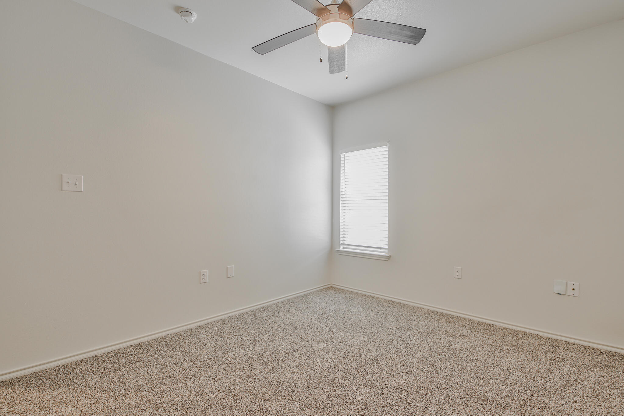 5512 Kemper Street Lubbock, TX 79416 - Photo 18 of 34 an empty room with a chandelier fan and windows