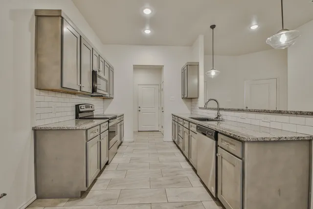 a large kitchen with granite countertop a sink and a stove