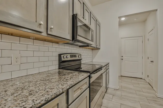 a kitchen with granite countertop white cabinets and stainless steel appliances