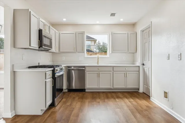 a kitchen with stainless steel appliances a sink cabinets and a wooden floor